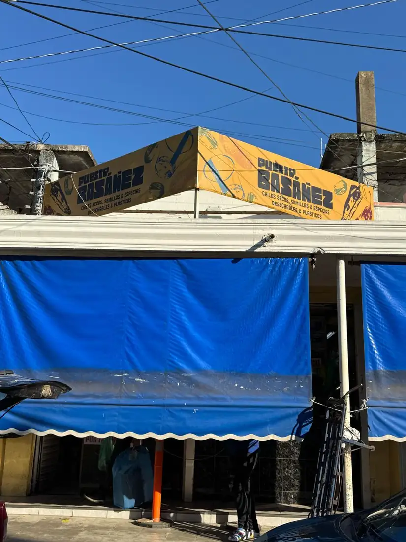 Fachada de Puesto Basáñez, toldo azul con el letrero del negocio